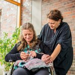 Eine Ehrenamtliche schaut einer Bewohnerin beim Stricken zu.