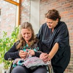 Eine Ehrenamtliche schaut einer Bewohnerin beim Stricken zu.