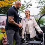 Ein Pfleger hilft einer Seniorin beim Aussteigen aus dem Fahrdienst.