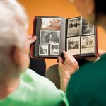 Eine Pflegerin schaut gemeinsam mit einem Bewohner des Pflegeheims ein Fotoalbum an.