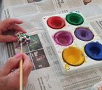 Hände einer Seniorin beim Wasserfarbenmalen.