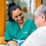 Eine Pflegerin massiert die Hand einer Bewohnerin.